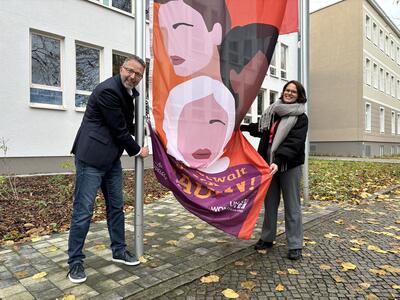 Landrat Alexander Tönnies und Gleichstellungsbeauftragte Valérie Stroh hissen die Aktionsfahne zum Tag gegen Gewalt an Frauen vor der Kreisverwaltung.